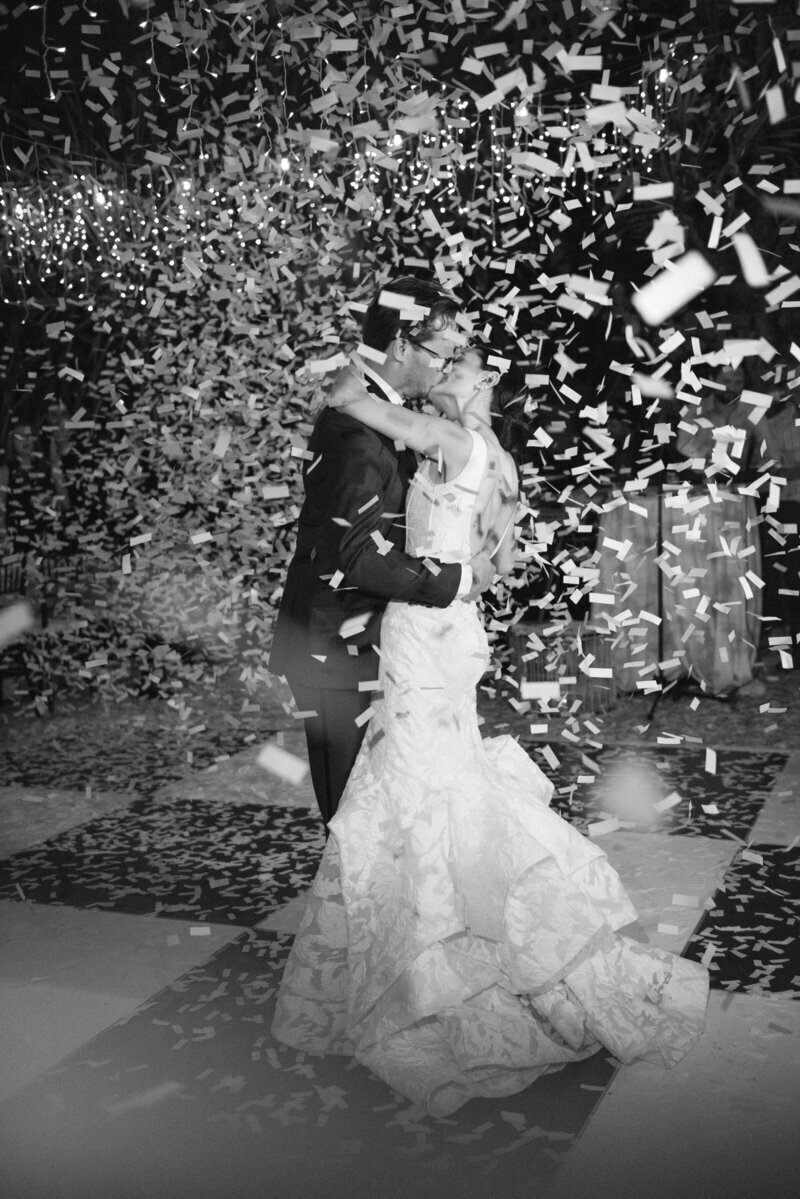 wedding couple kissing on dancefloor under confetti captured by a Miami editorial wedding photographer