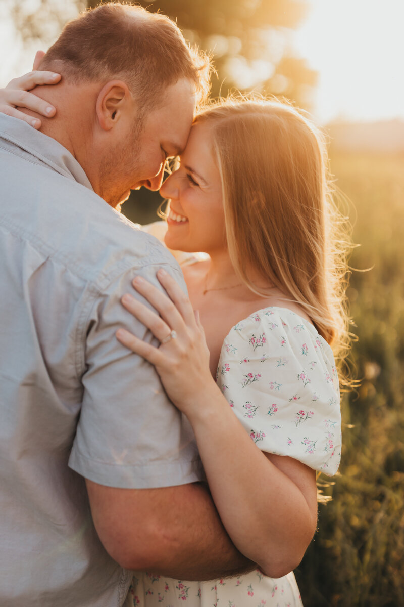 couples photo in a field at sunset embracing one another 