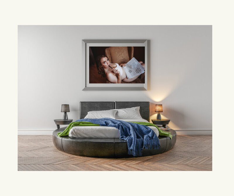 A framed portrait of a woman sitting in a chair with a crossword puzzle  above a bed in Minneapolis Mn