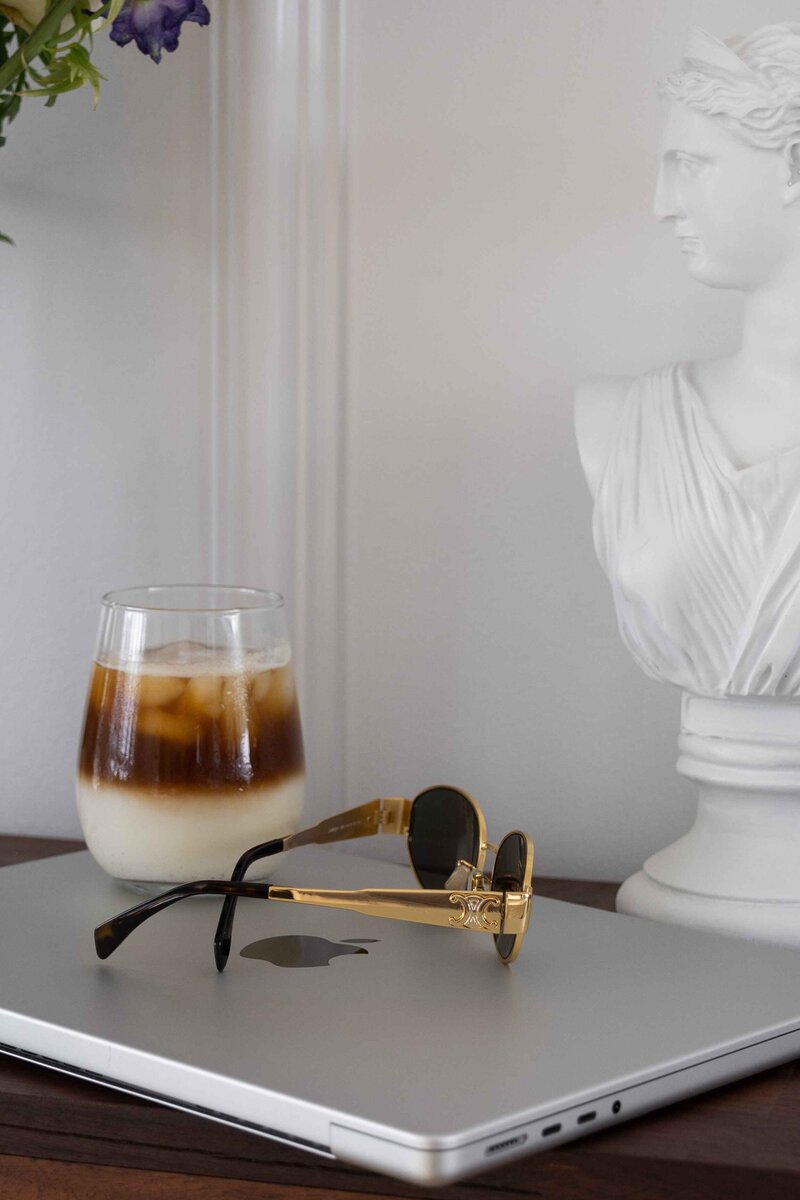 Iced coffee, sunglasses, and sculpture beside closed laptop – Bespoke Web Design