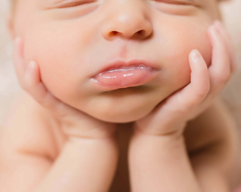 Picture of a newborn with chin resting on hands and milk on her lips