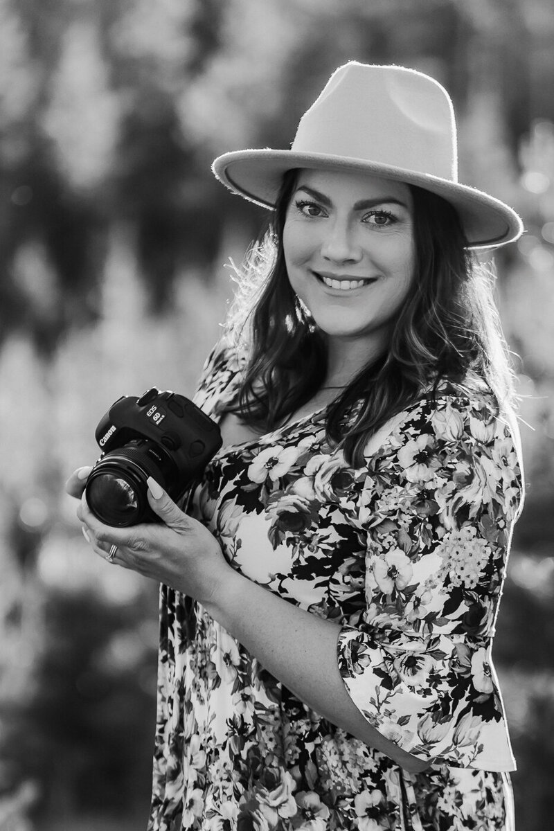 woman in hat holding camera while smiling