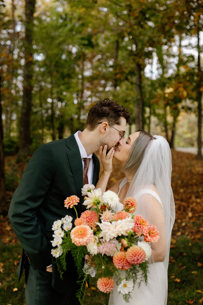 couple on wedding day kissing in front of trees