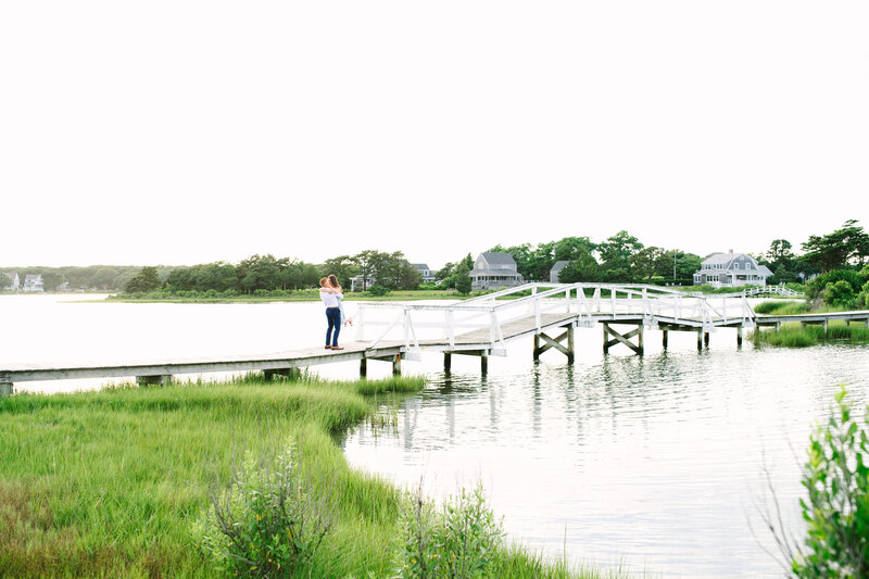 a guy lifting up just engaged fiance on a bridge during a falmouth surprise proposal session