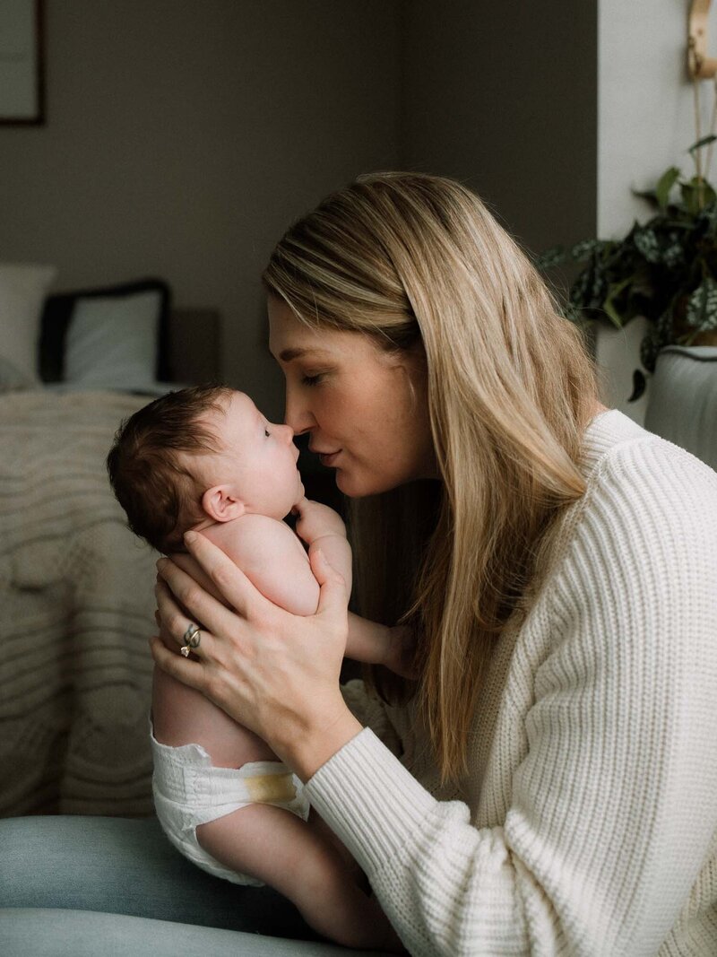Mother holding her newborn baby close during an in-home lifestyle photography session in Canyon Lake, CA.