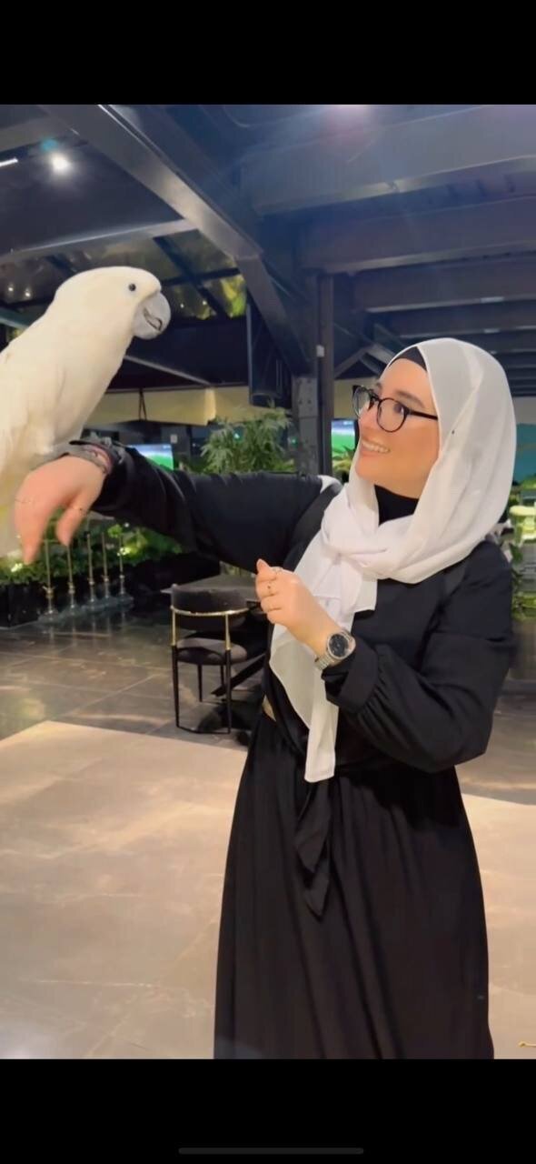 Ayah Official smiling while interacting with a white bird, showing her personality, authenticity, and joyful approach to life and business.
