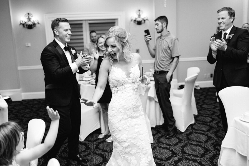 Minnesota bride in an elegant white wedding dress, joyfully high fiving a flower girl as they do grand entrance. Captured by Toly Dzyuba Photography.