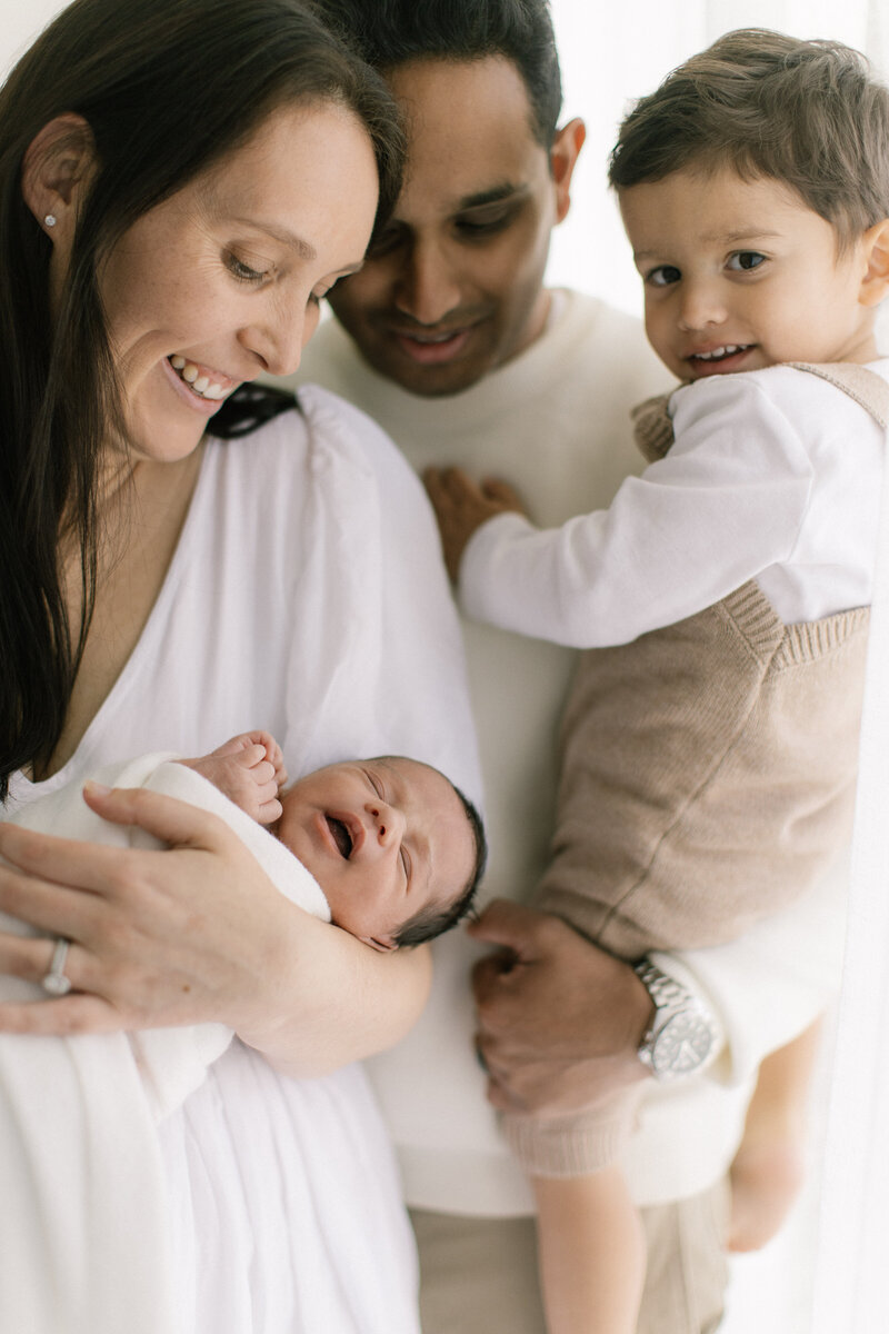 Newborn baby peacefully swaddled and sleeping in a neutral-toned wrap, photographed by Penrith newborn photographer in a cozy, softly lit studio setting. 