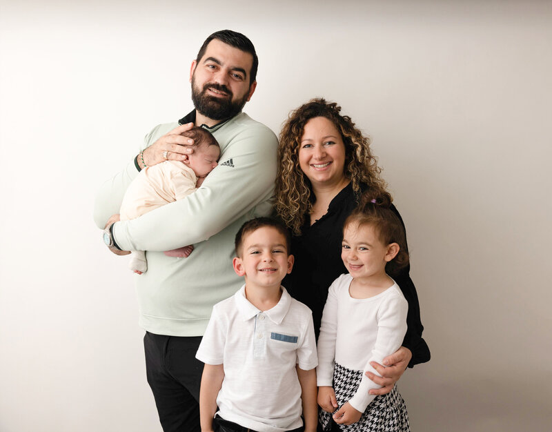 Family of five posing for family photo session with a newborn baby boy. 