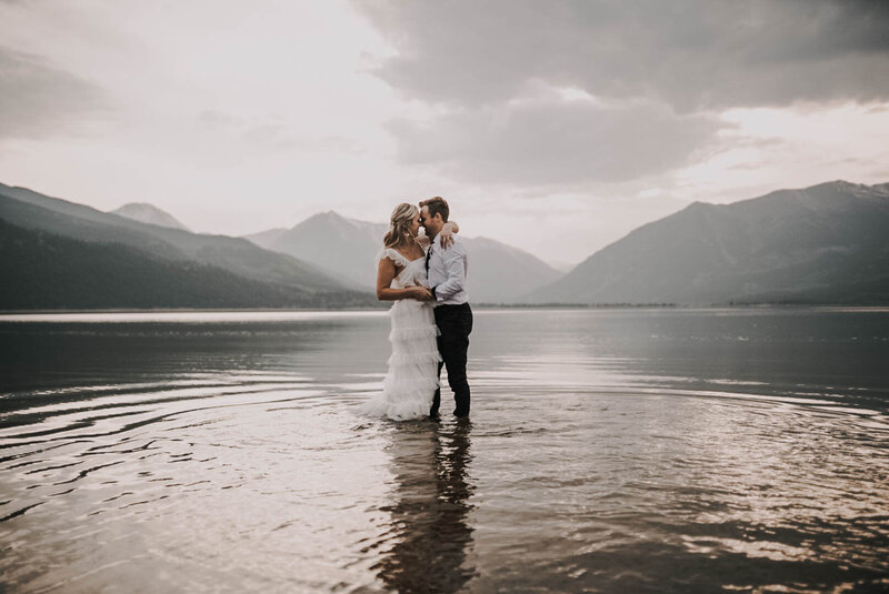bride and groom holding eachother on water