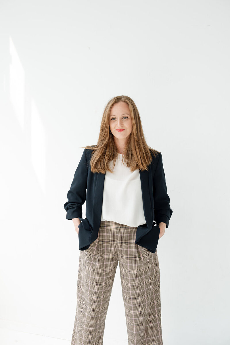 Professional branding portrait of a woman in a blazer and plaid trousers, photographed in Irvine with a clean white backdrop.