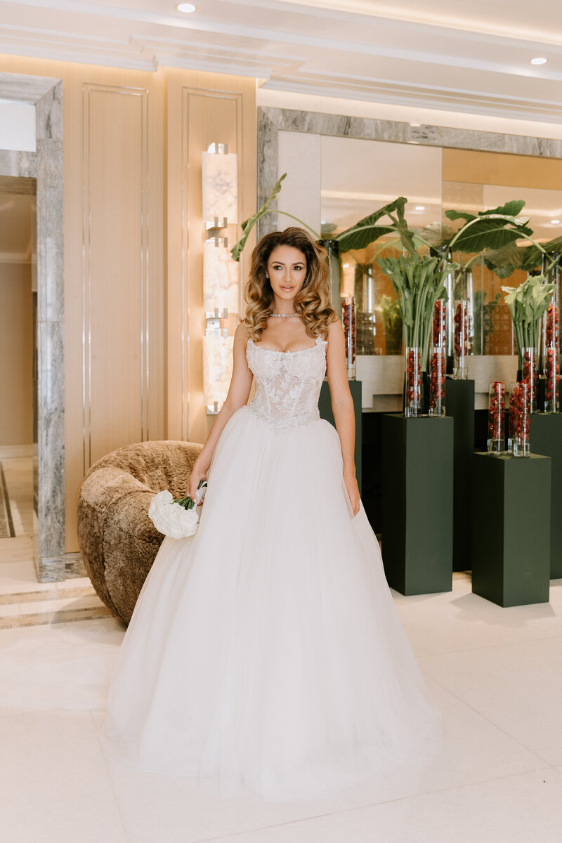 Bride in a Galia Lahav dress at The Berkeley Hotel in London holding elegant white bridal bouquet.
