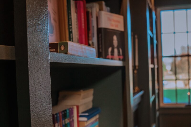 Bookshelf side view of moss green colored builtins filled with books