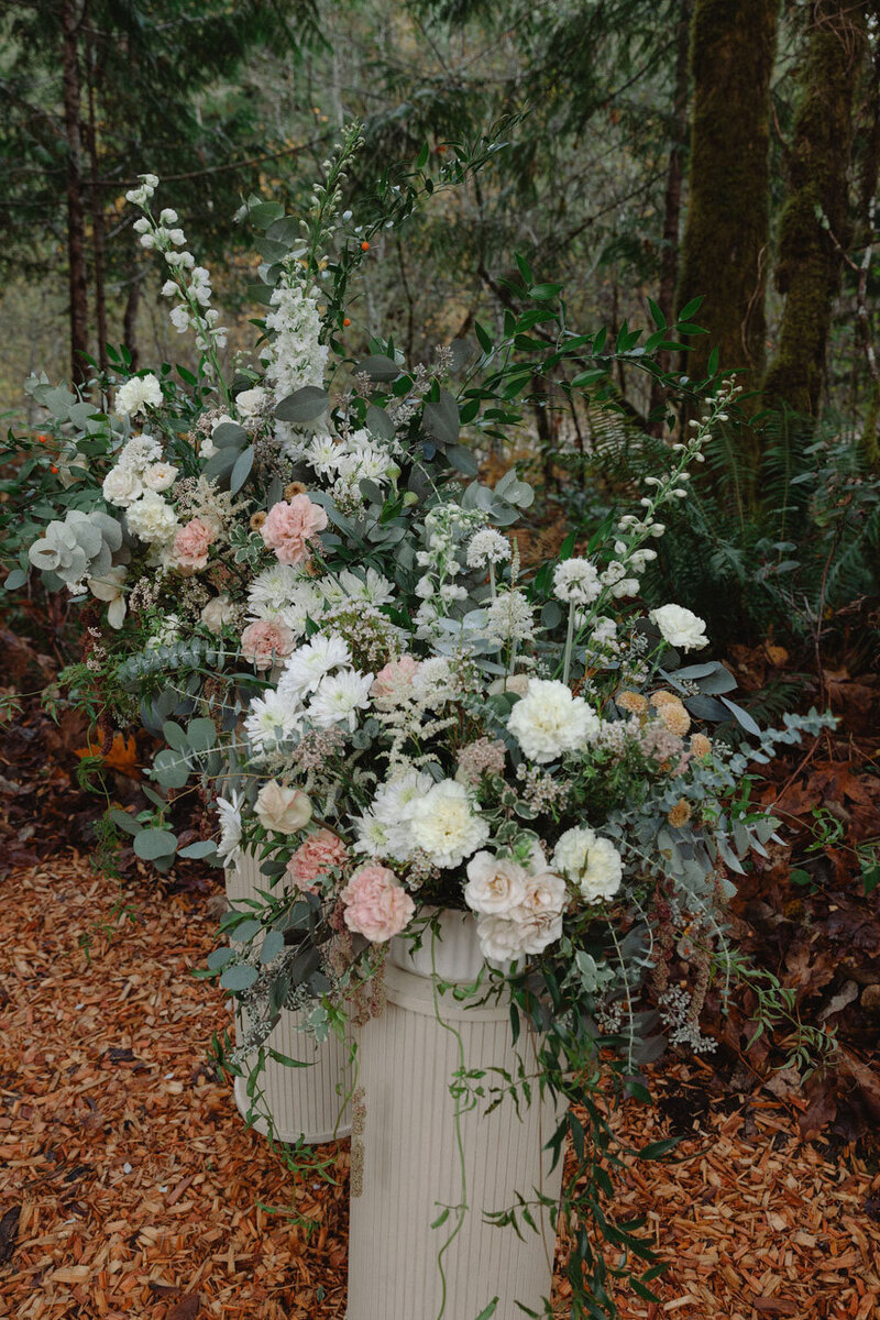 Matching floral arrangements displayed in tall cream vases