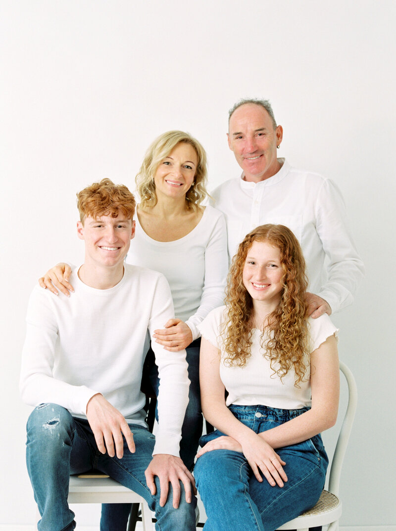 Family of 4 pose for photo in a studio portrait session