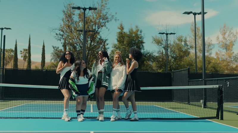 a group of women on a tennis court laughing.