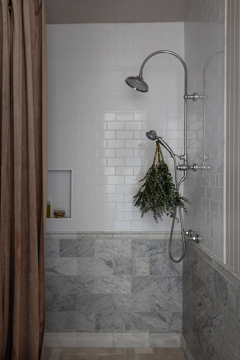 A mixture of classic subway tile and gorgeously veined Carrara Marble took this hall bathroom walk-in shower to the next level. By Jessa Myer Interiors. 
