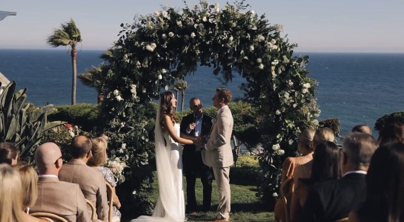 wedding couple holding hands during ceremony on california beach