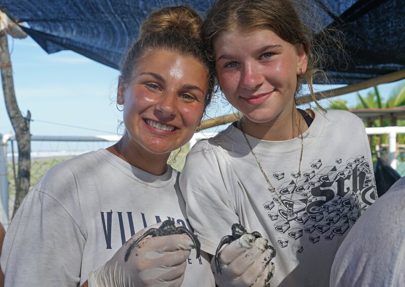 Two young women holding baby sea turtles in Costa Rica
