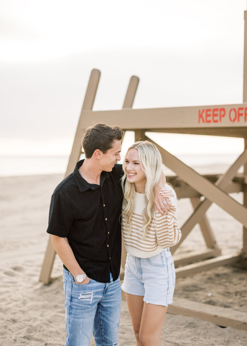 candid and fun couple photo on the beach with lifeguard stand
