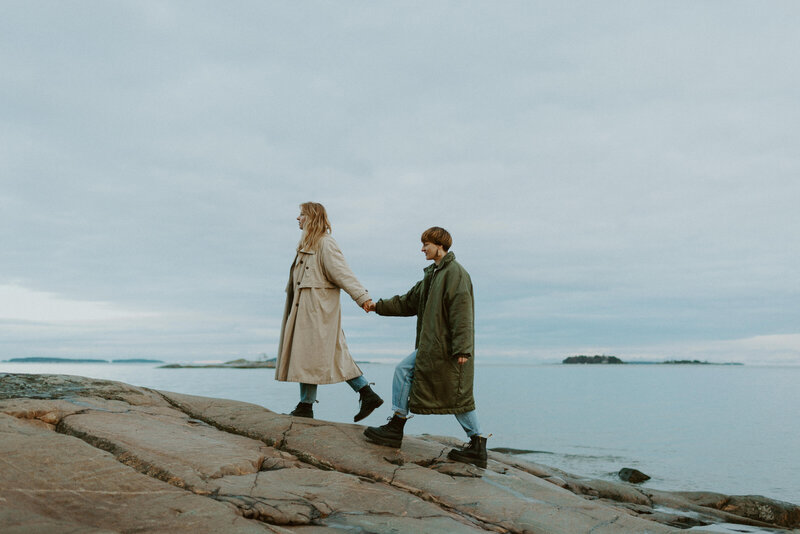 Aikuiset siskot kävelevät käsi kädessä Kallahden rantakallioilla Helsingissä