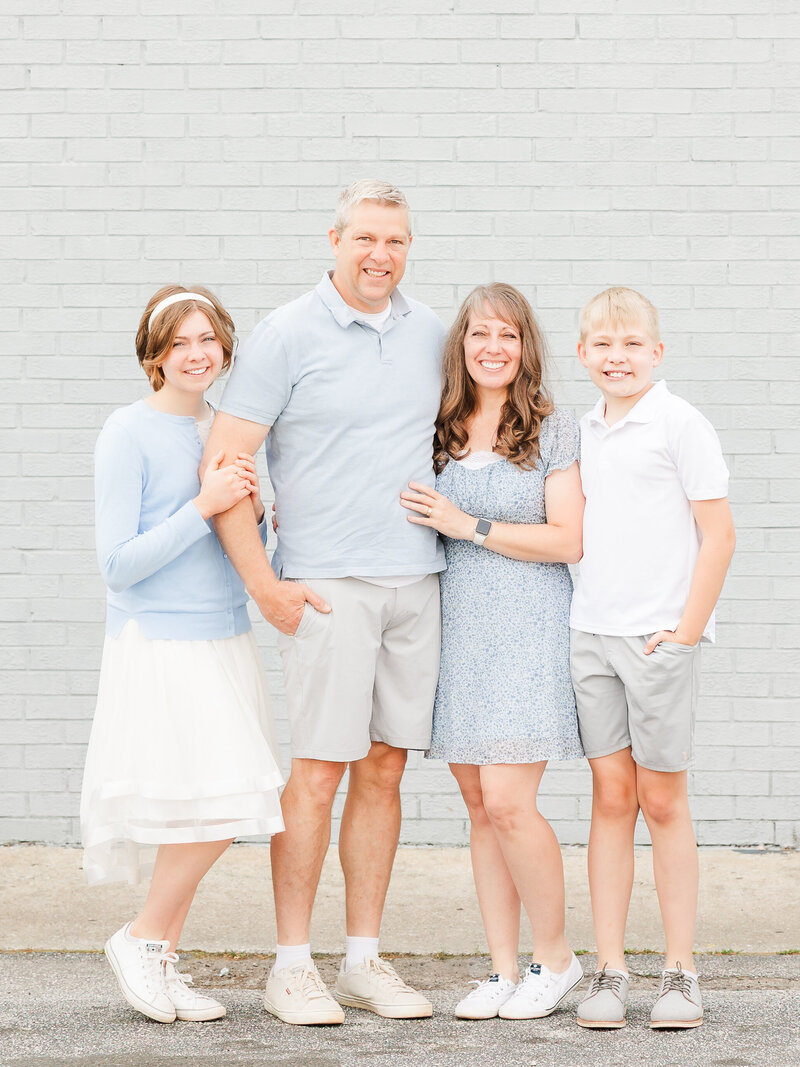 Jennifer Hall Photography, LLC team by a light blue wall with blue and white outfits.   
