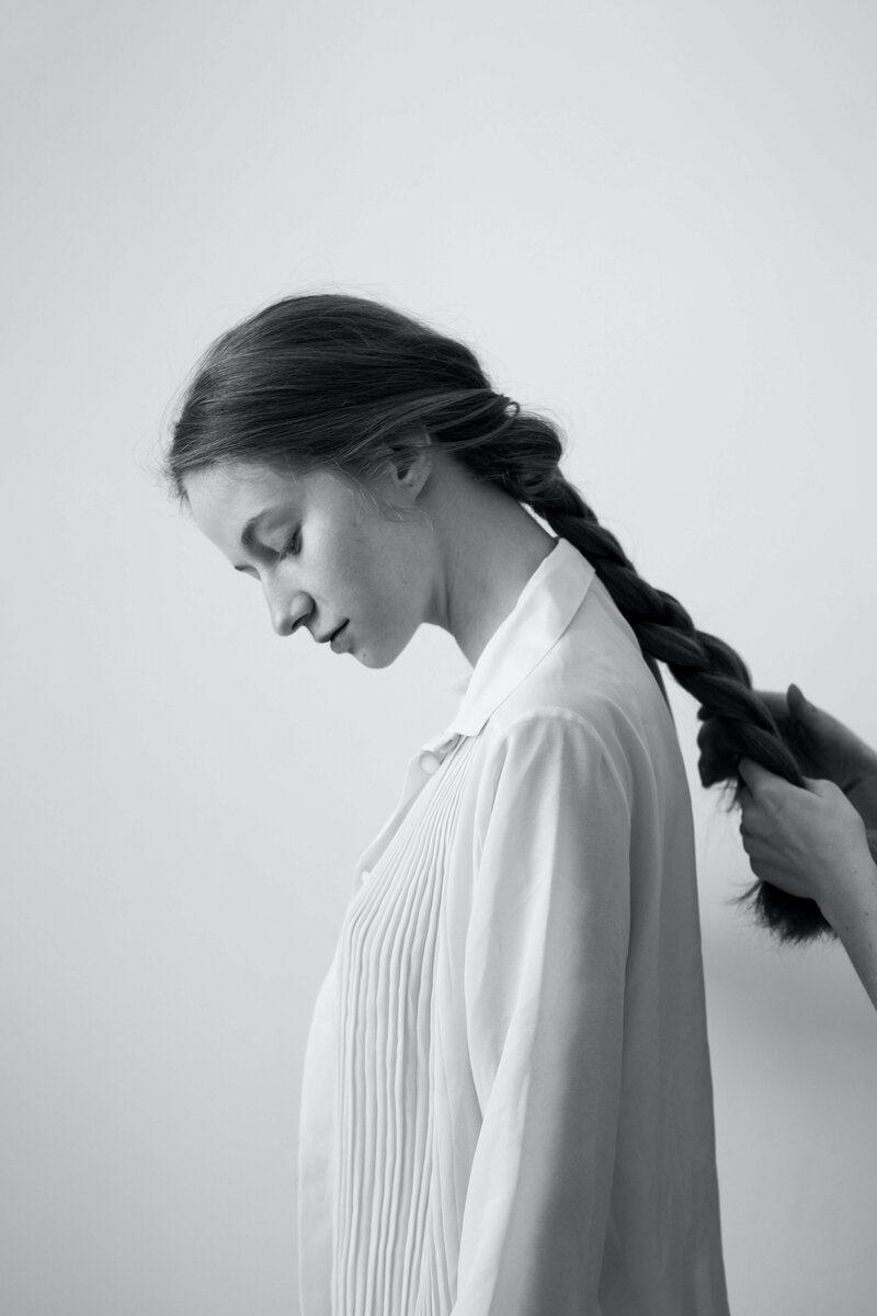 Black and white photo of woman getting her hair braided and styled.