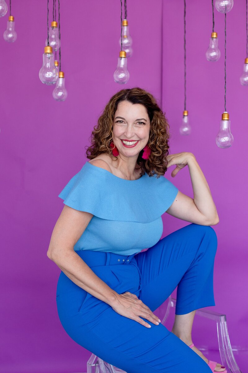Amanda Hennessey, public speaking coach smiling in front of purple background