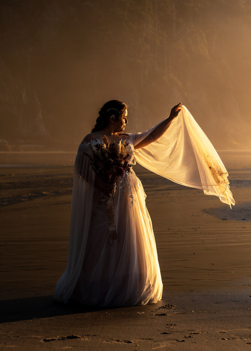 during her oregon ccoast elopement, a bride twirls in her wedding dress. Her gauzy sleeves billow in the golden light.