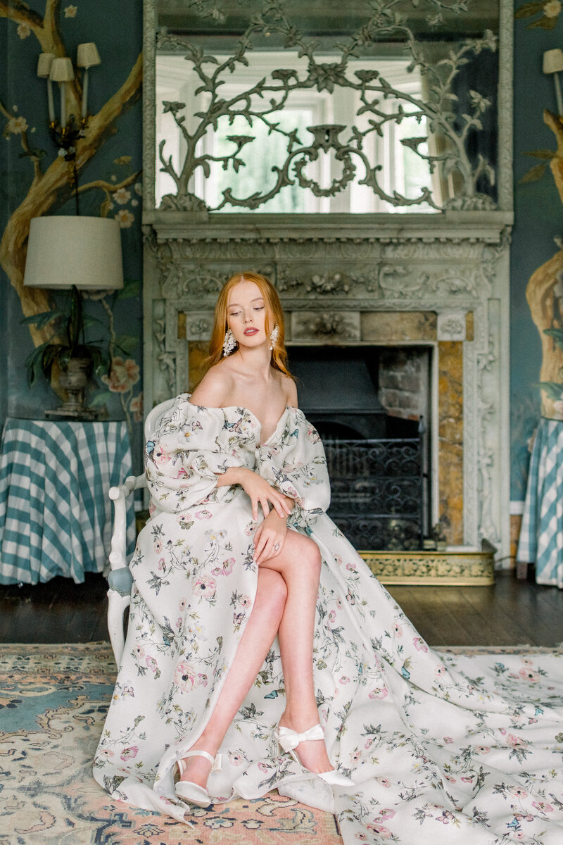 Embark on a visual journey with Tiffany Longeway's photography, showcasing a European luxury bride in her unique custom hand-painted blue floral wedding dress. Exuding a sense of royal elegance, the bride stands regally in an opulent room with historic charm, her gown a work of art that commands attention. This image captures the essence of bespoke bridal fashion, reflecting a commitment to unparalleled luxury and individuality on the most enchanting day.