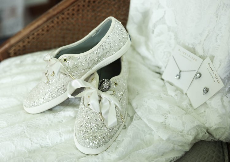 brides shoes and jewelry laid on top of her dress