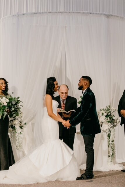 real bride wearing a custom bridal veil and laughing with her groom at the altar.