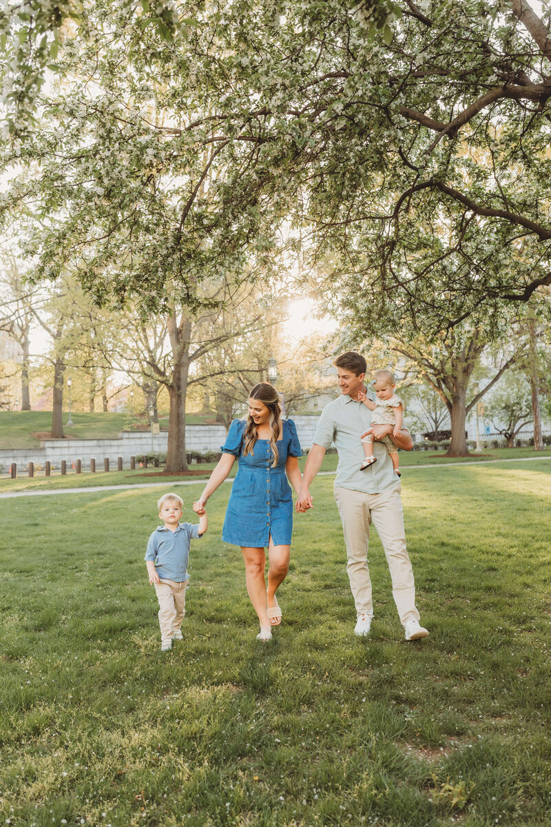 mom, dad, and little boy holding hands walking while dad carries little girl 