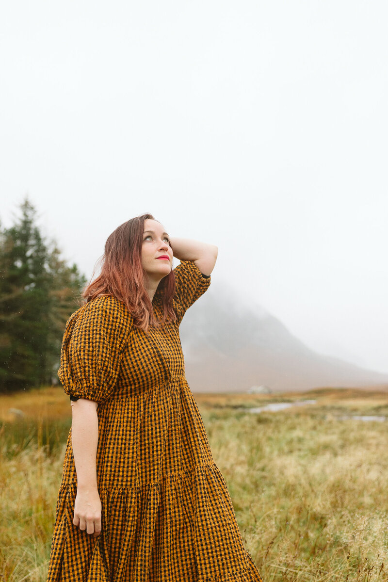 red hair photographer looks towards moody sky
