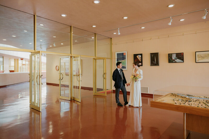Bride and groom walking through Civic Center exhibit during elopement.