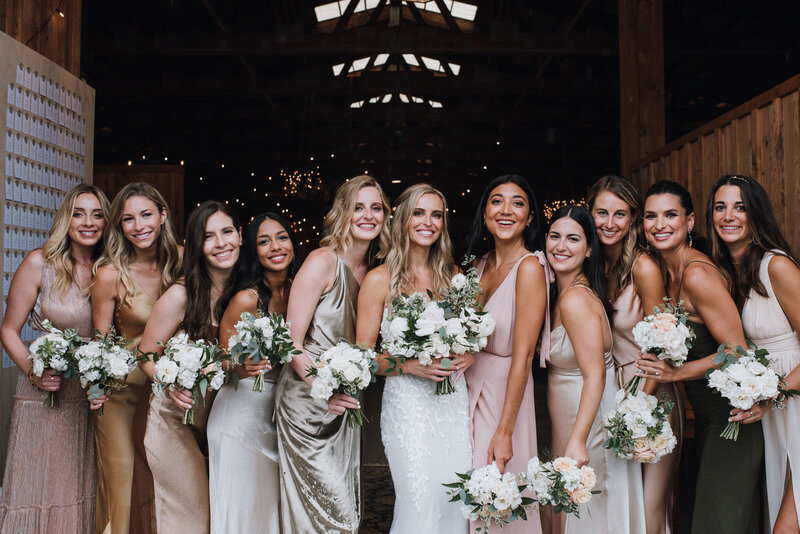 A bride and her bridesmaids wearing shades of blush ivory gold champagne and olive green satin