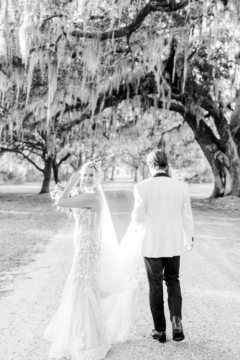 bride and groom walking under oak trees at beaufort wedding