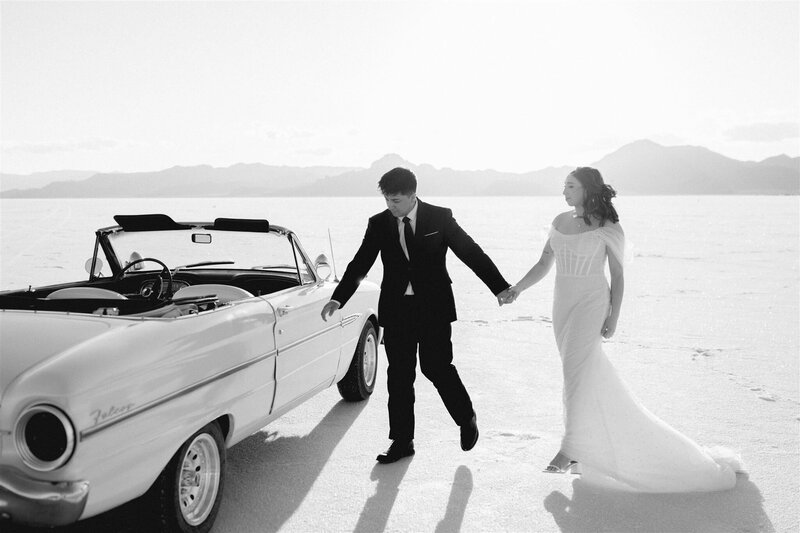 Couple walking to an old getaway car during the salt flats elopement.