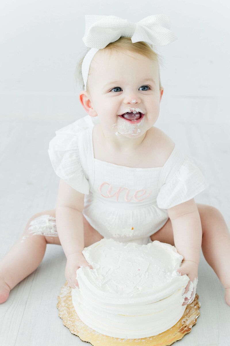 girl sits with cake smiling for milestone photos in mini model rep program