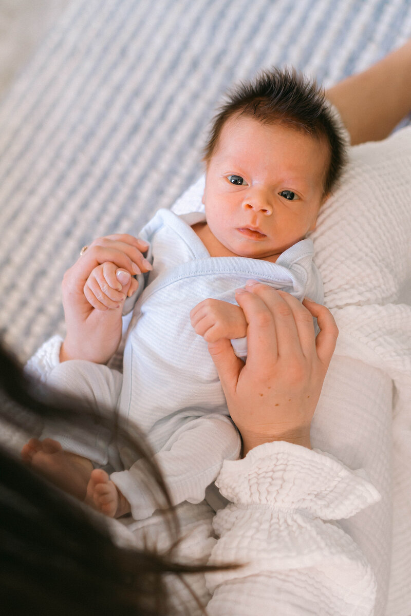 Tender moment between dad and his newborn son on the couch, bathed in dreamy natural light during an in-home session by Sugar House Utah newborn photographer.