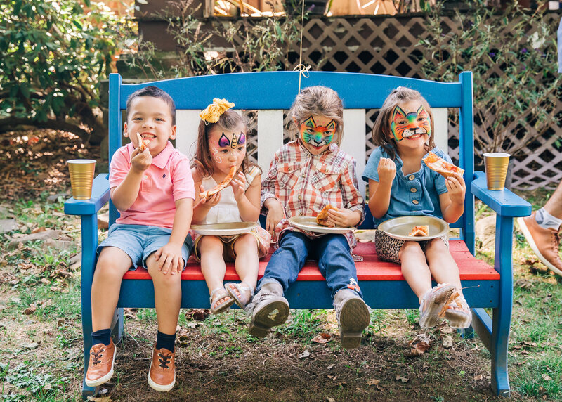 Kids with painted faces eat at a casual party
