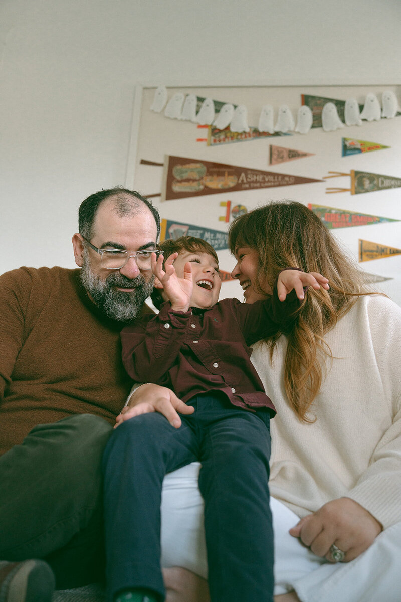 Parents laughing with their son on the couch during a relaxed at-home family photography session in Orange County.