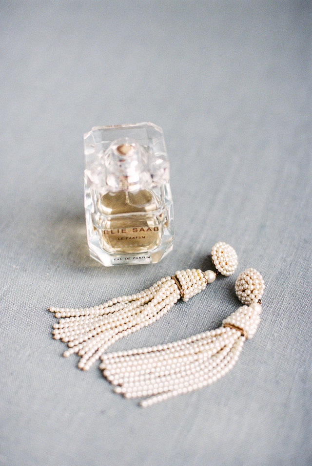 Designer pearl tassel wedding earrings with a bottle of Ellie Saab perfume