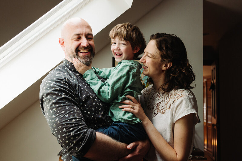 Husband, 5 year old son, and photographer Adrianne all hugging under a skylight in their bedroom