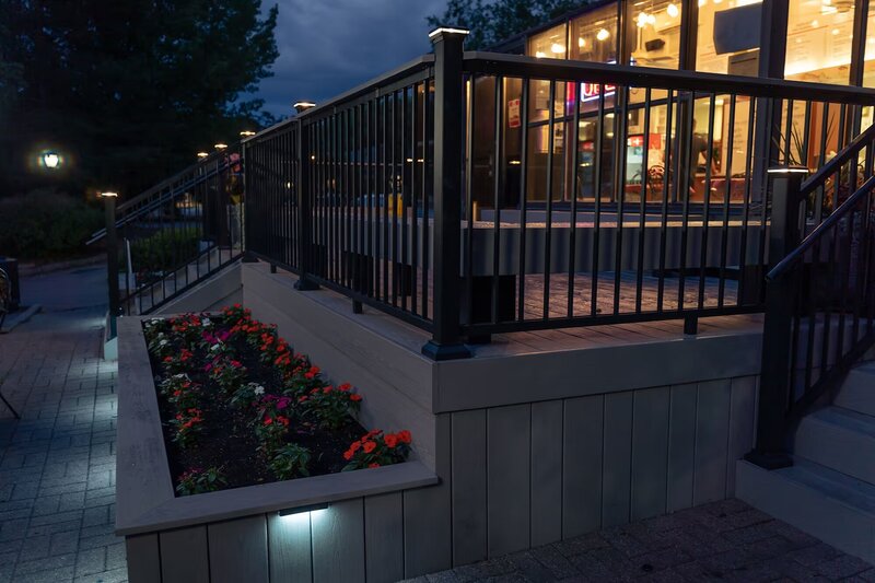 Nighttime view of built-in flower beds with integrated LED lighting on the front of a PVC deck. 