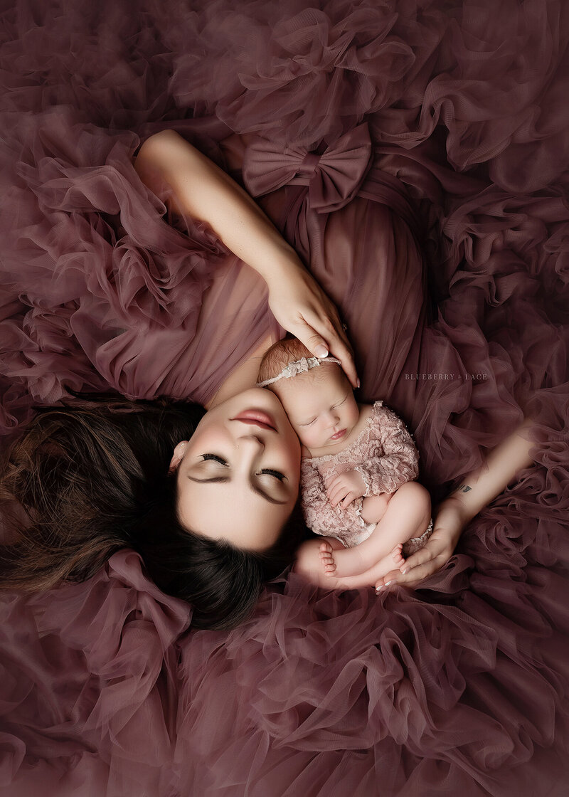 mauve colored couture gown laying on the floor with mother and baby for newborn photo shoot