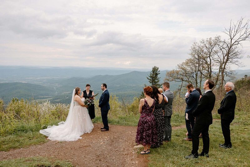 A couple says their vows while their immediate family watches. The Blue Ridge Mountains are in the background. Shenandoah Elopement photographer