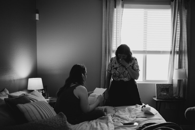 bride and mother in law reading letter to each other on their wedding day