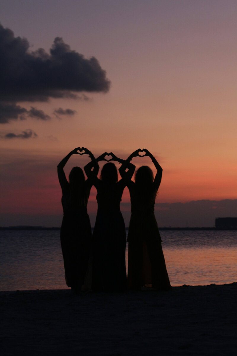Three women holding up heart hands in a nurse community 