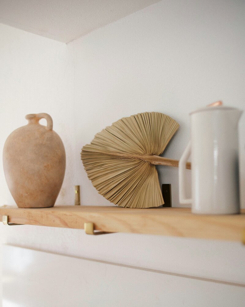 Vases and dried leaf decorations on a wooden shelf